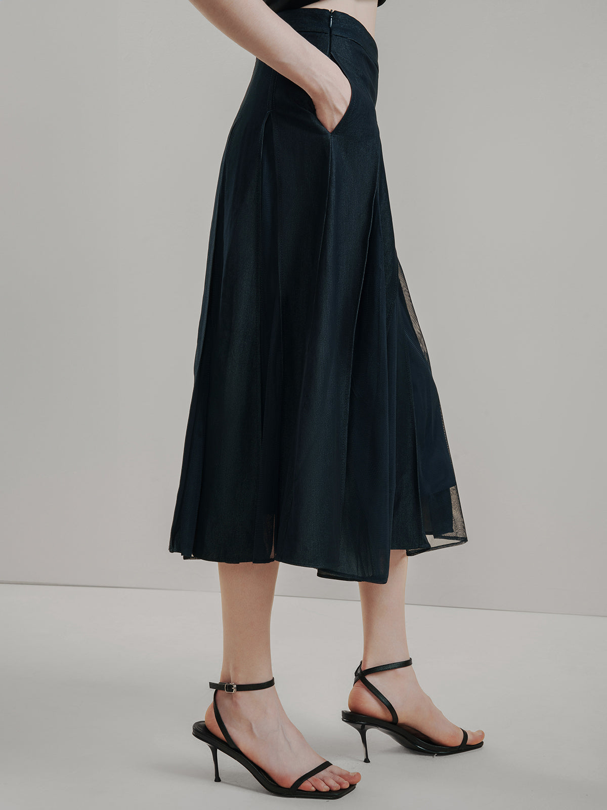 Elegant black pleated midi skirt with sheer mesh inserts, featuring A-line silhouette and structured design, perfect for work or evening outfits