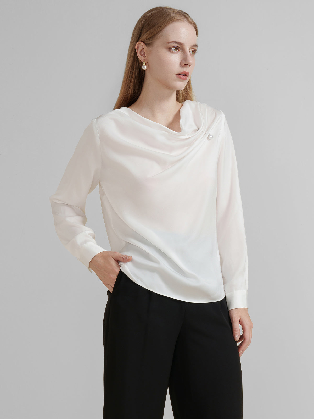 Chic long-sleeve blouse with an asymmetrical draped neckline and pearl detail.