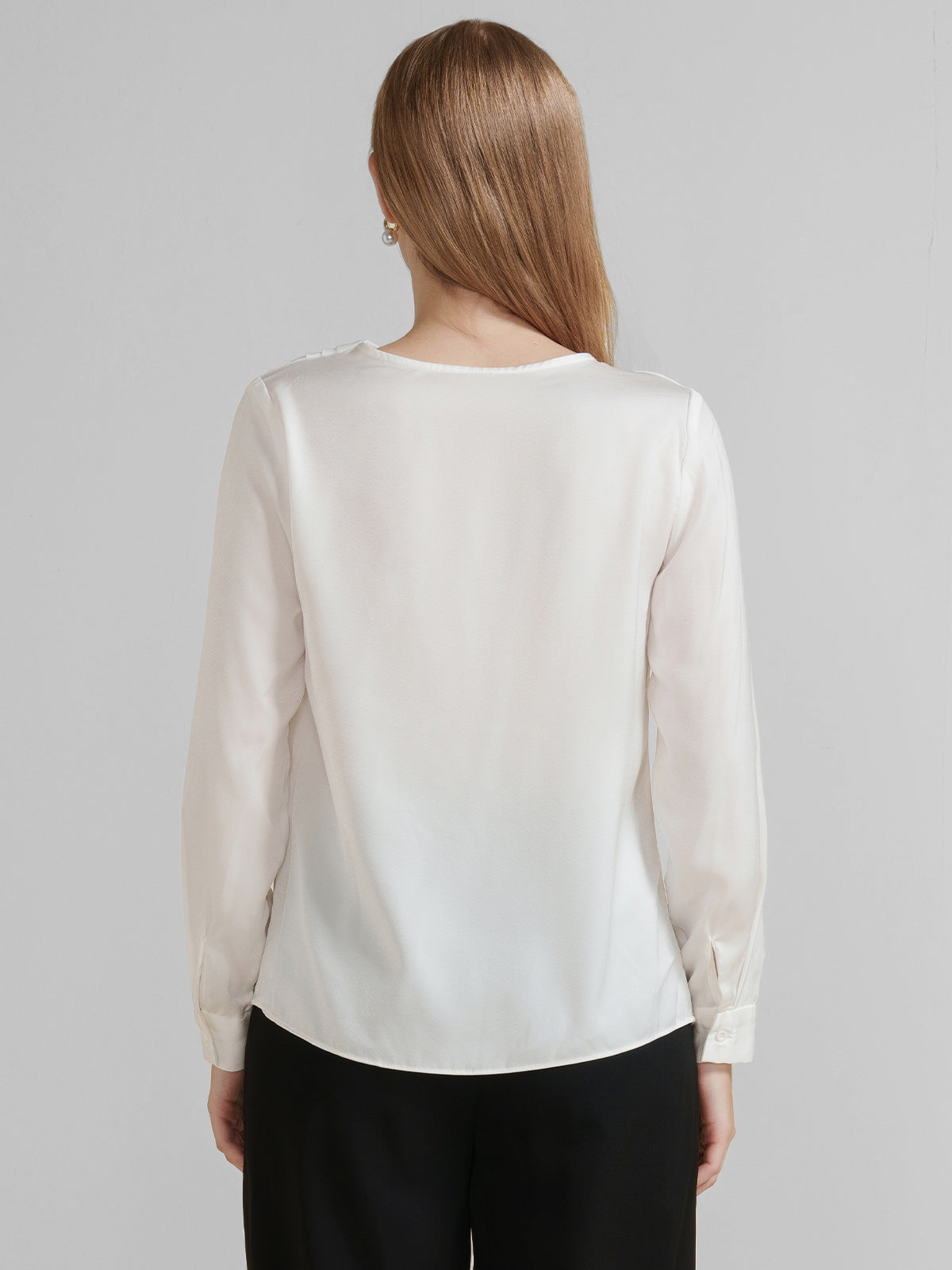 Chic long-sleeve blouse with an asymmetrical draped neckline and pearl detail.