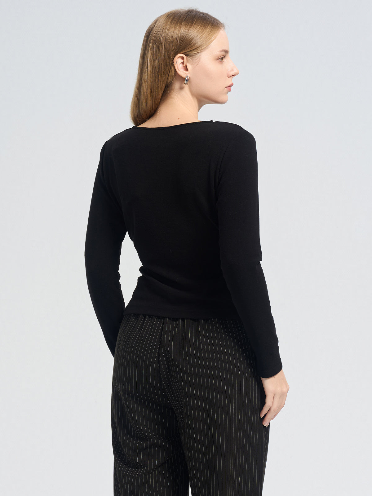 Asymmetric black long-sleeve top with a crossover pleated front