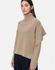 Elevate your winter wardrobe with this chic solid-colored turtleneck sweater, showcasing special sleeve detailing that creates a shawl-like effect for a unique and stylish look.