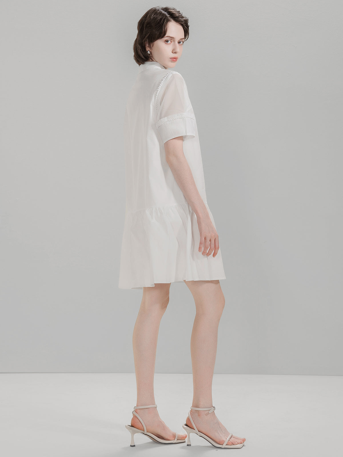 Side view of S·DEER white dress with a loose fit, mesh sleeves, and ruffled hem
