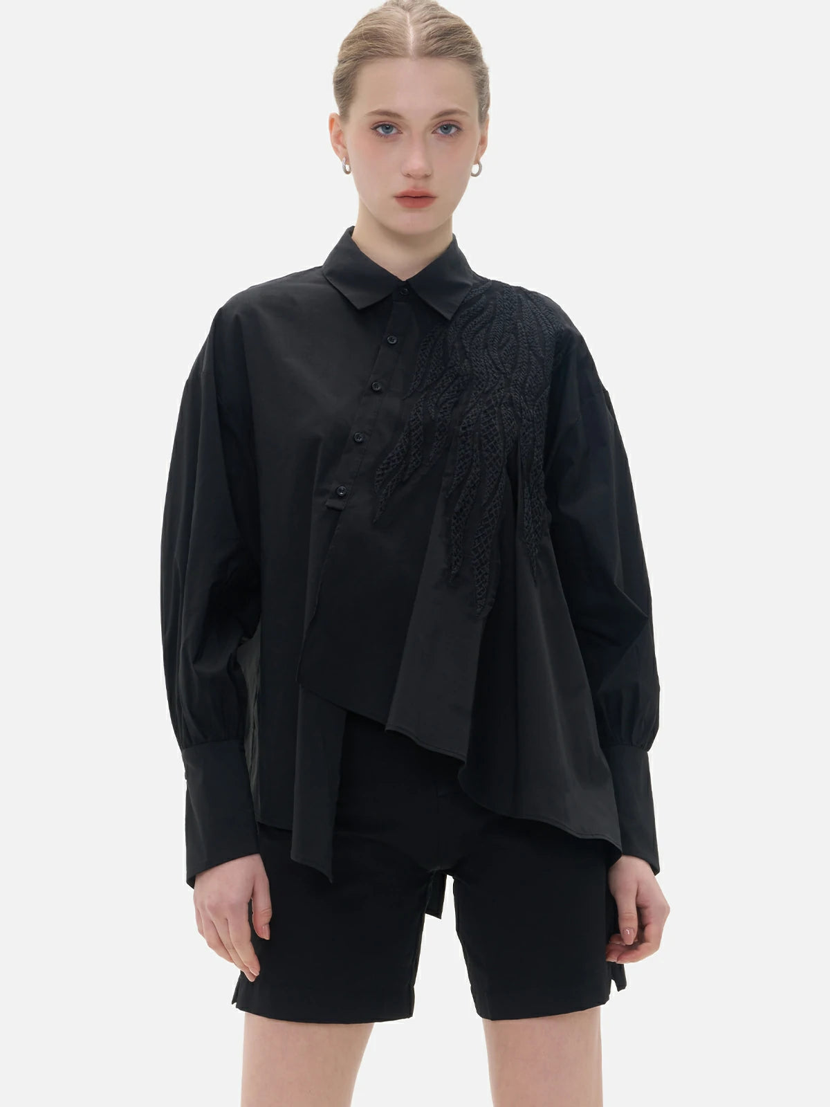 Fashionable black shirt with a front irregular cut, back slit, and diagonal button closure.