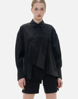 Fashionable black shirt with a front irregular cut, back slit, and diagonal button closure.