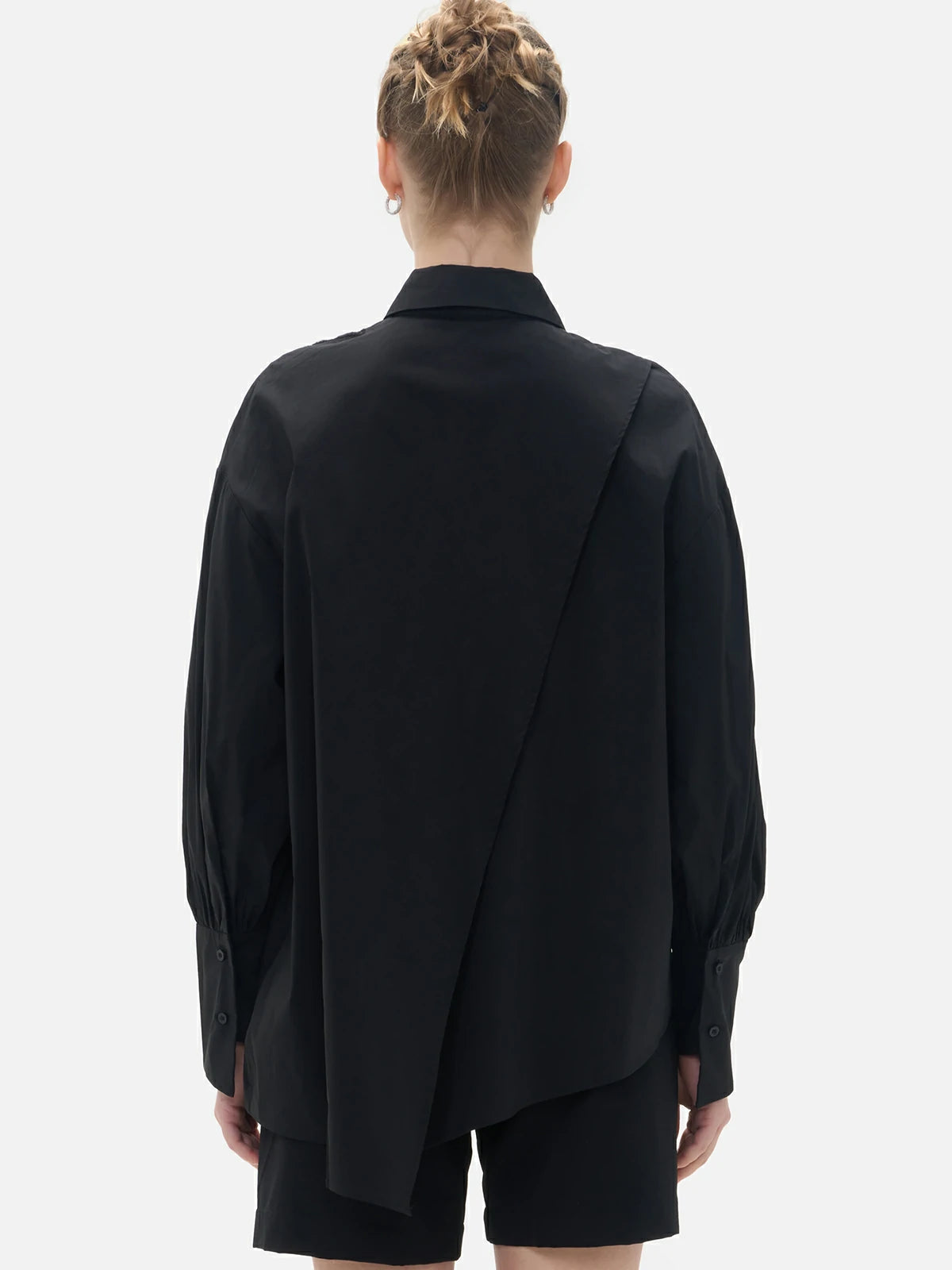 Uniquely designed black shirt with an front irregular cut, back slit, and diagonal button closure.