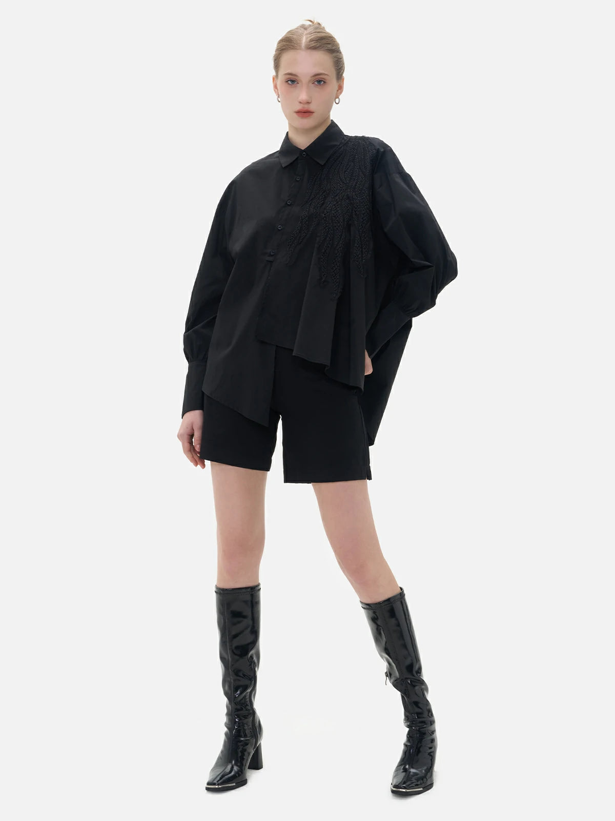 Stylish black shirt with distinctive features, including front irregular cut, back slit, and diagonal button closure.