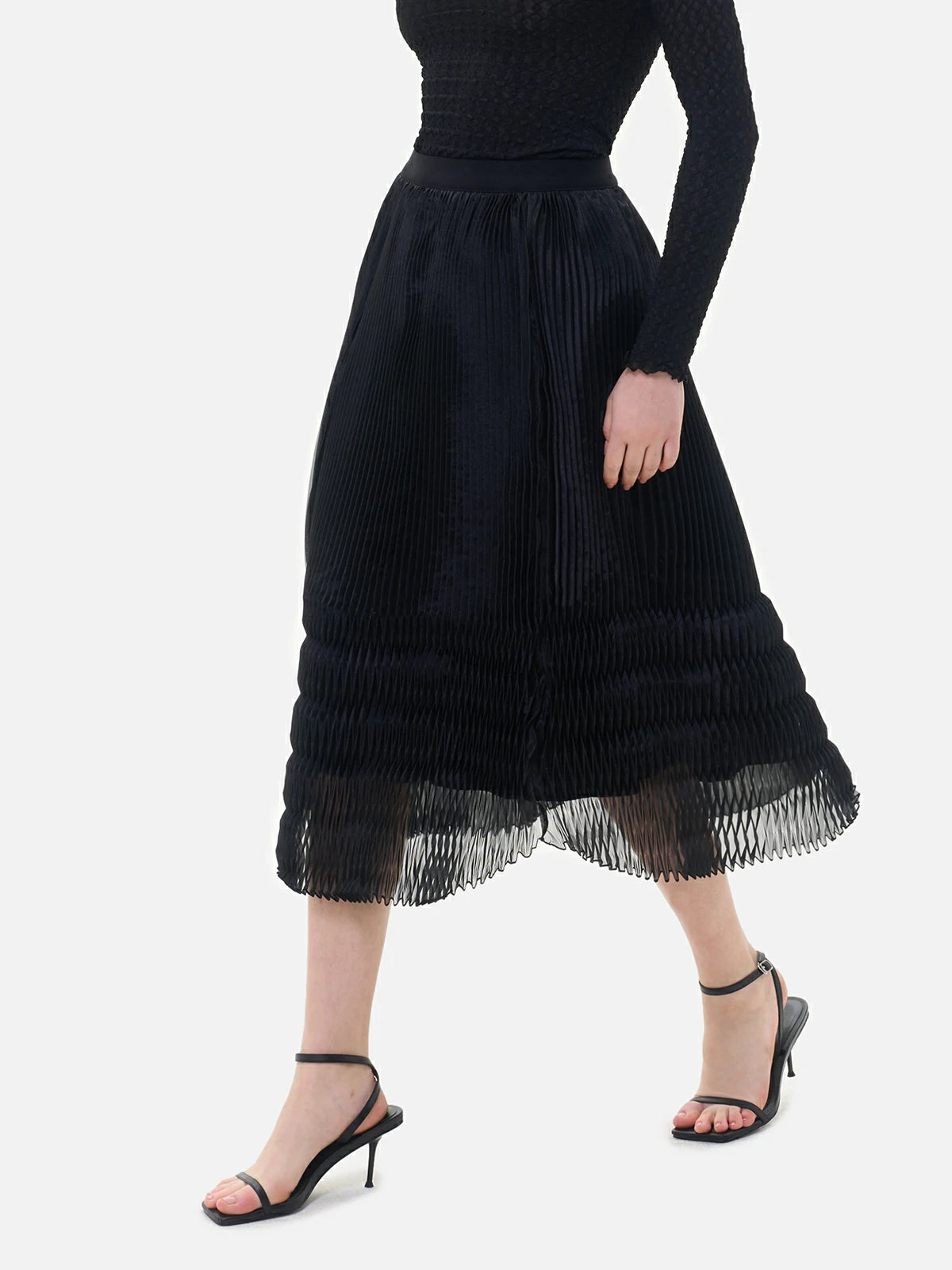 A black semi-transparent skirt with V-shaped pleats, presenting a mysterious allure and flowing lines.