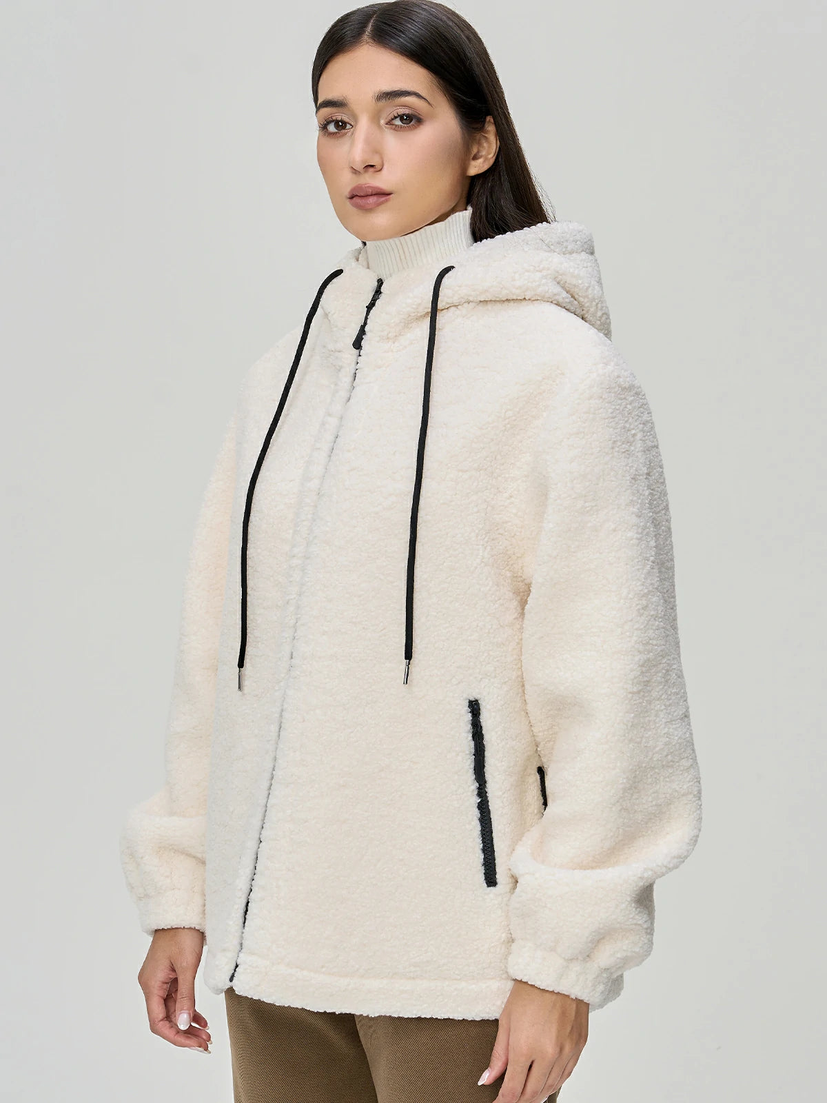 Elevate your winter wardrobe with this chic beige shearling hooded jacket, showcasing symmetrical zippered pockets for a stylish and functional look.