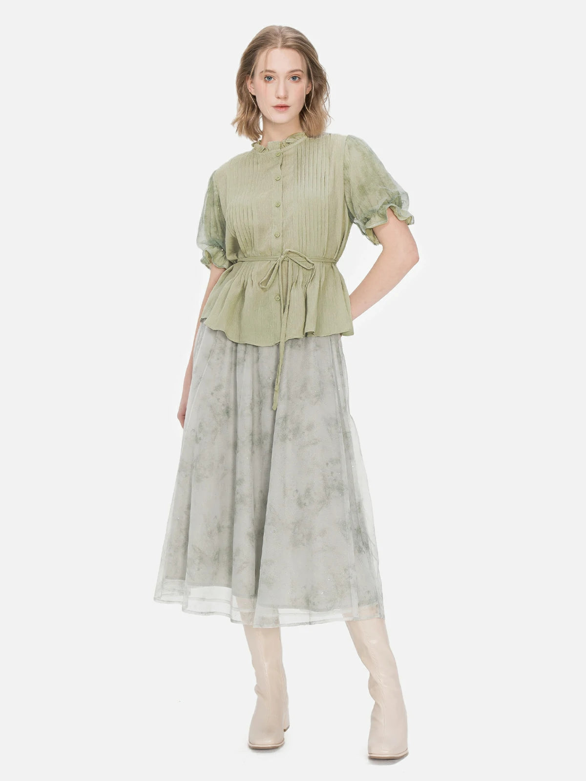 An elegant green short-sleeved blouse featuring a unique accordion pleat design, mesh bubble sleeves, and waist tie for a distinctive look.