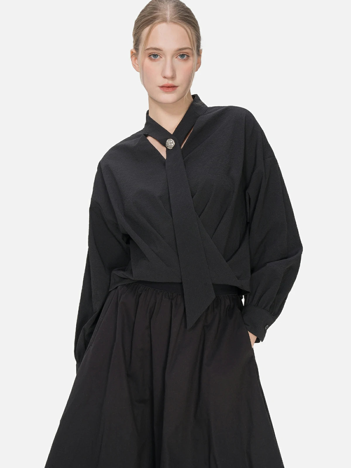 Fashionable silhouette in a V-neck blouse with unique cascading ribbons and a cross-pleat hem.