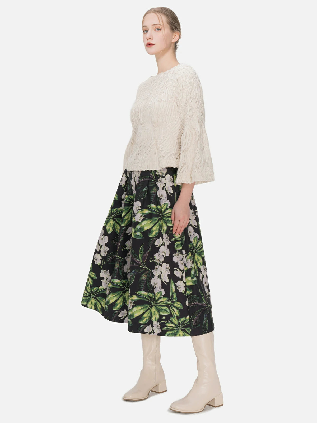 Youthful and versatile A-line midi skirt with a high-waisted silhouette, showcasing a vibrant color-blocked floral pattern and dynamic layered pleats for various occasions.