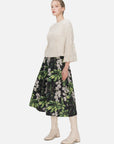 Youthful and versatile A-line midi skirt with a high-waisted silhouette, showcasing a vibrant color-blocked floral pattern and dynamic layered pleats for various occasions.