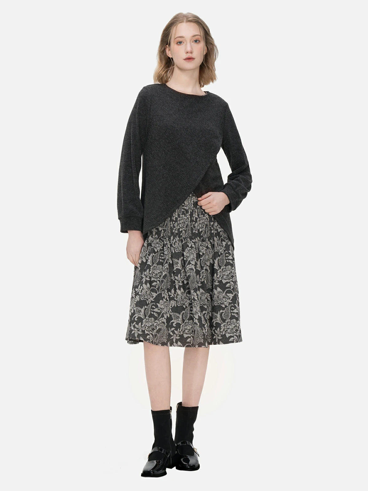 Stylish two-piece ensemble featuring a round-neck pullover sweater with an irregular hem design and a sleeveless dress adorned with a pleated floral print.