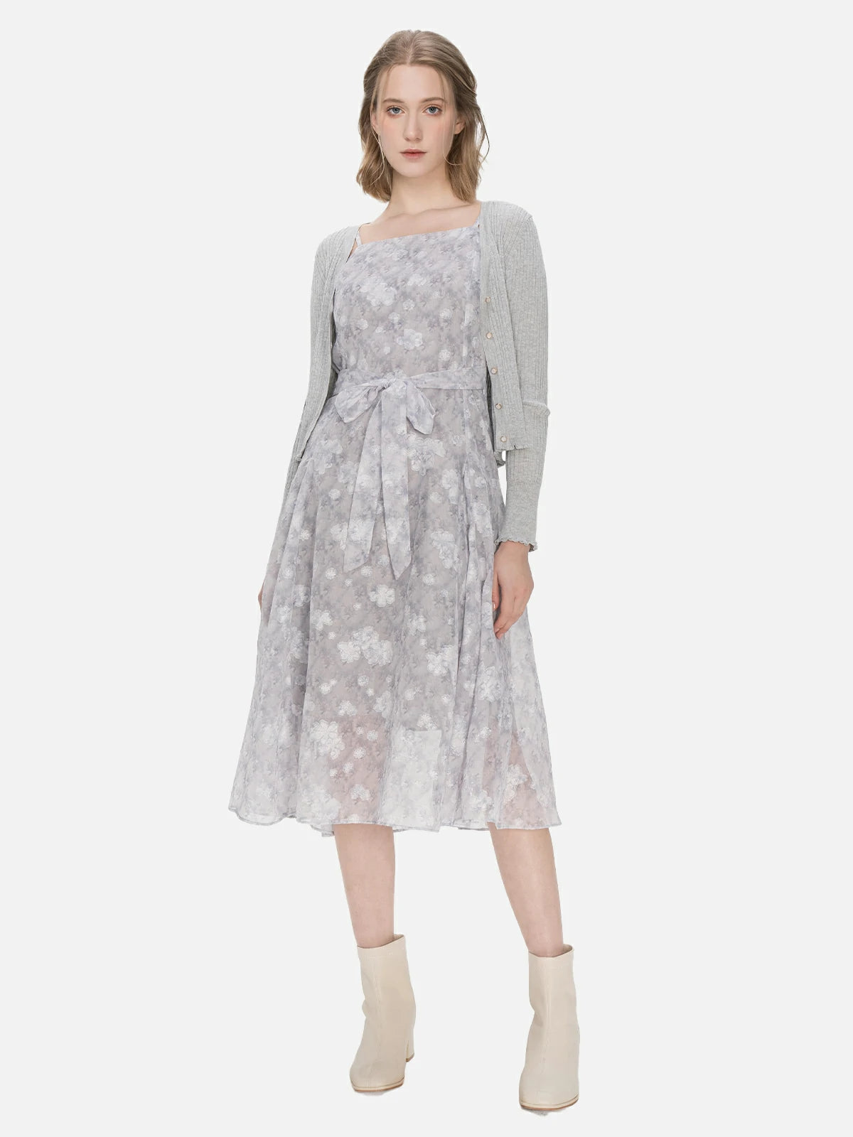 Define your fashion identity with this classic and stylish two-piece ensemble, showcasing a V-neck knit cardigan with ruffle hem and buttons, and a spaghetti strap floral chiffon dress in a gray color palette, creating a timeless and elegant outfit.