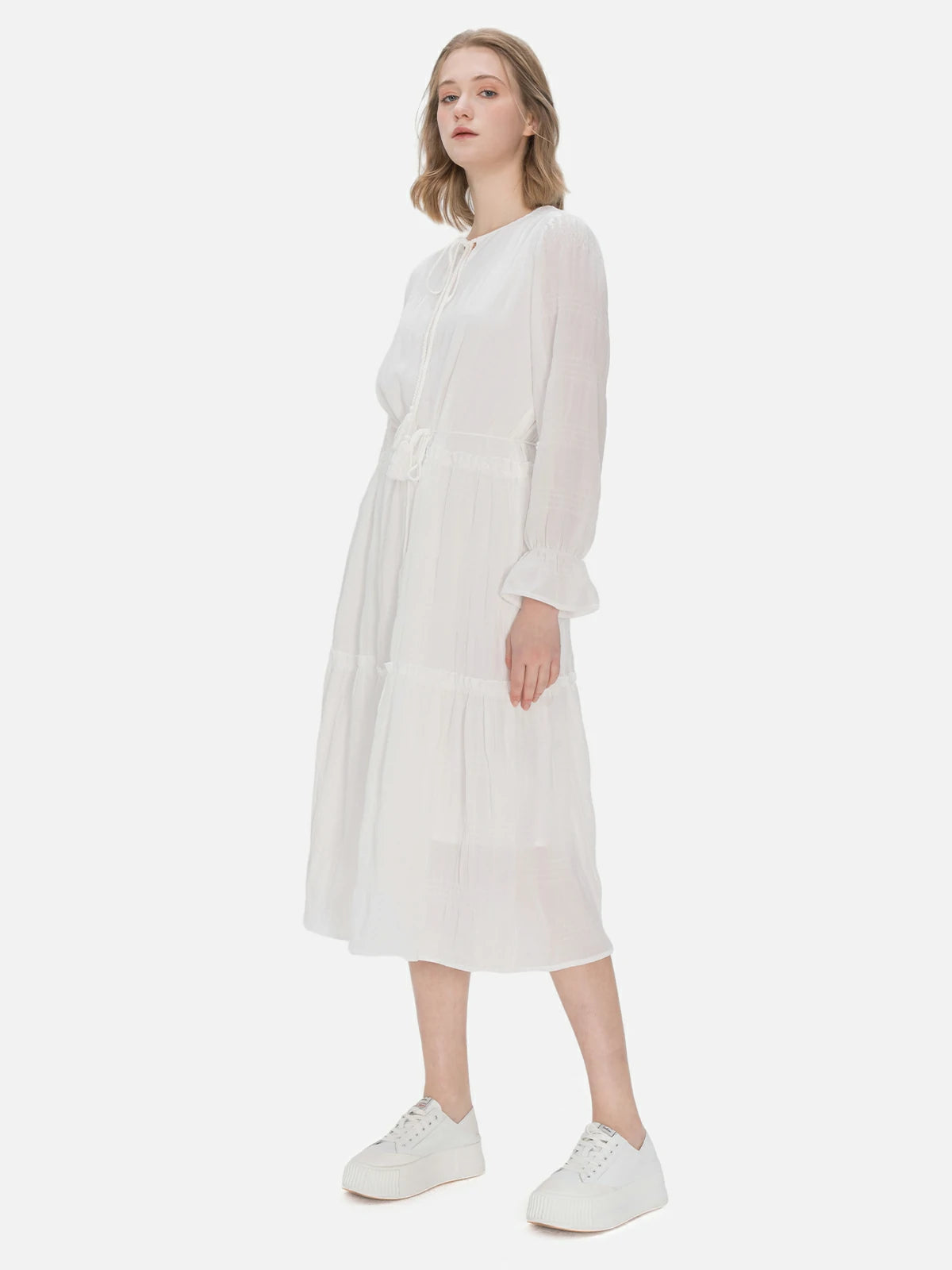 Tailored mid-length dress featuring white design, neckline tie, waist tie, and ruffle edges, providing a comfortable and stylish option.
