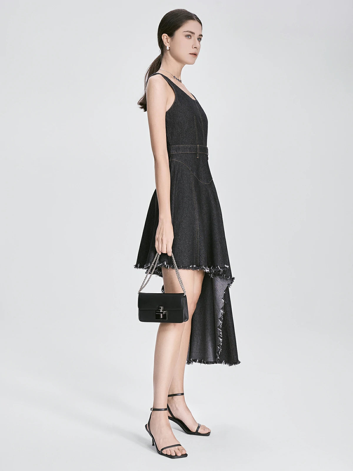 Black asymmetrical denim dress with raw edge detailing and fitted waist – side view