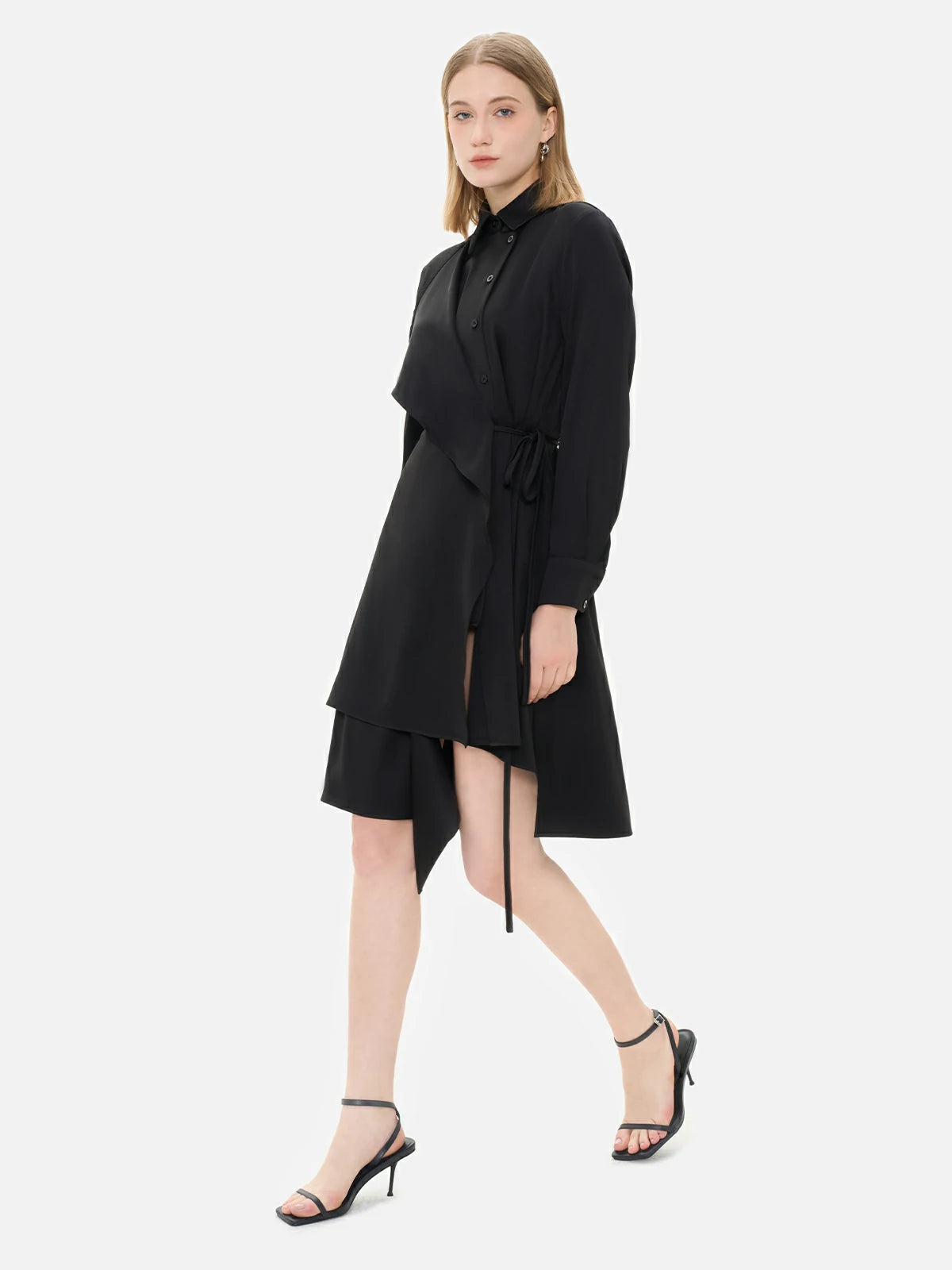 Experience the charm of this versatile black shirt dress, adorned with a waist-tie accent, irregular hem, and front paneling. 