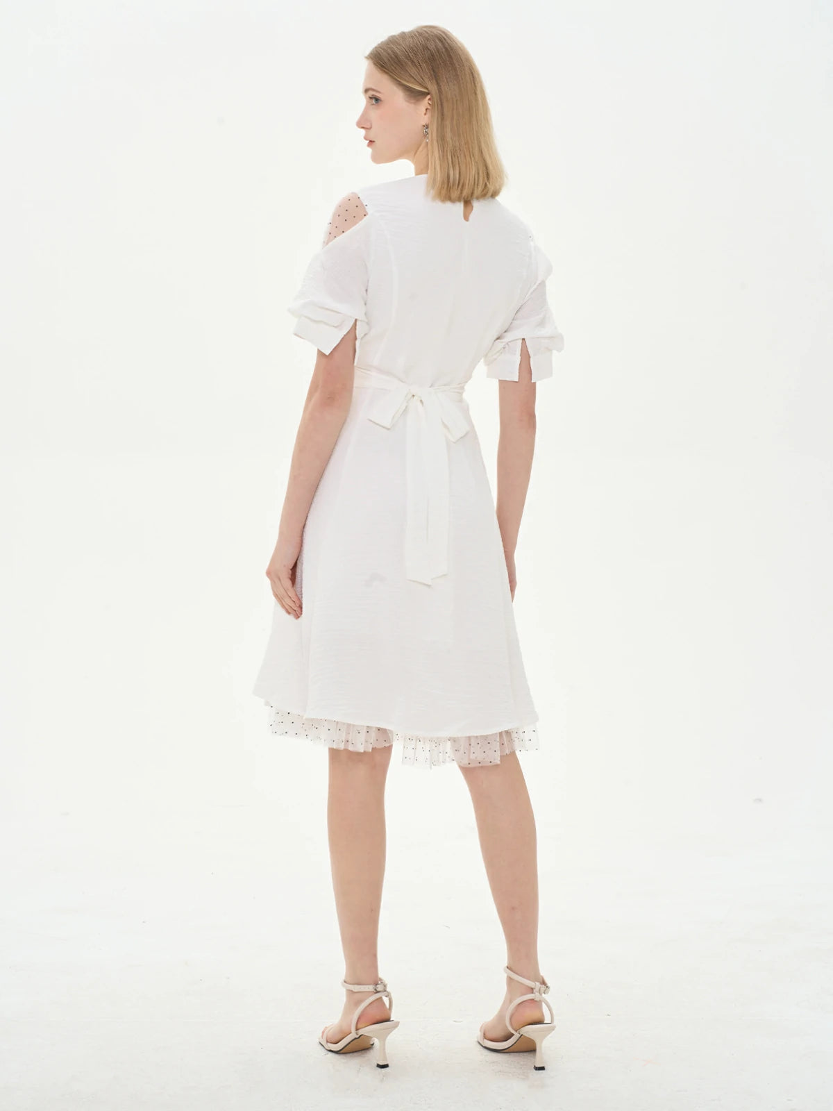 white dress with puffed sleeves and a lace-trimmed hemline, offering an elegant and feminine look