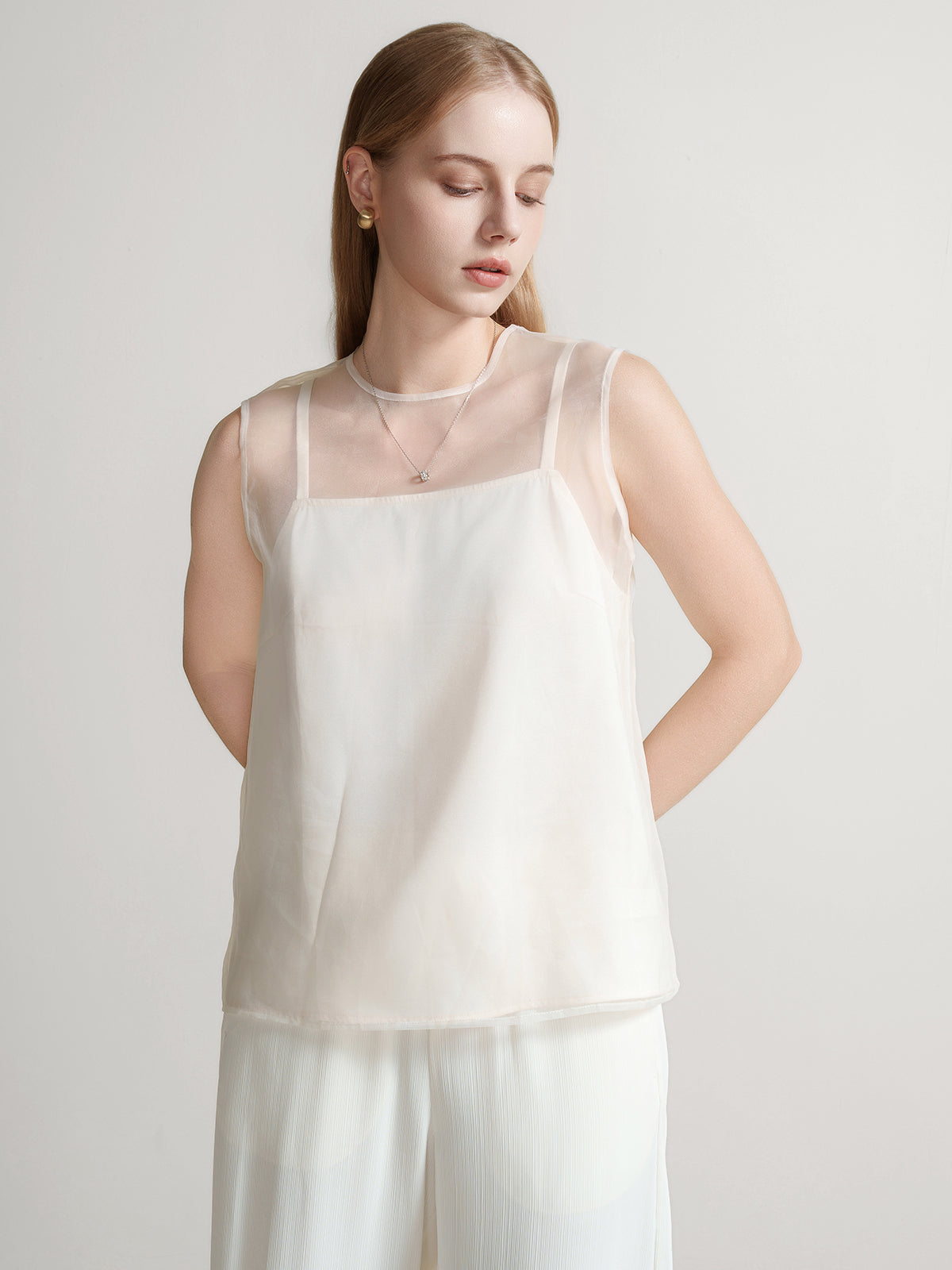 Minimalist sleeveless top in beige with a sheer round-neck overlay for a delicate layered look