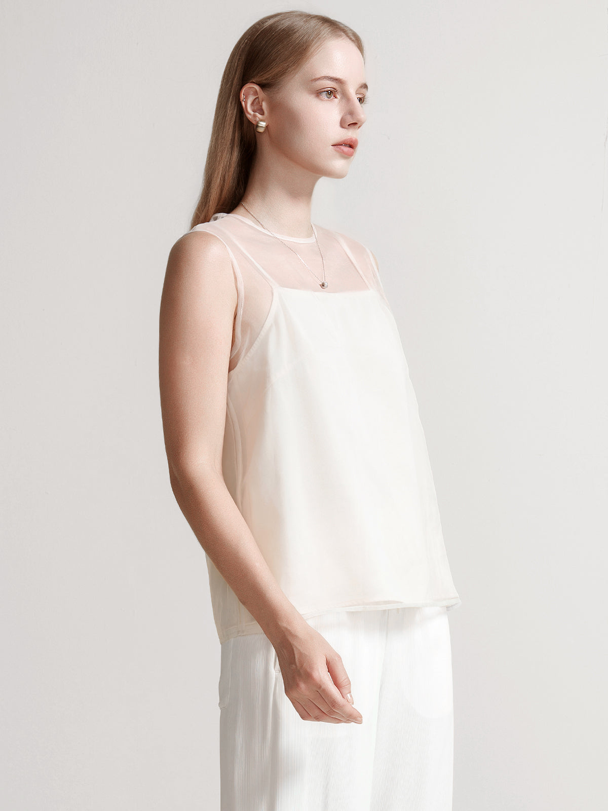 Elegant beige sleeveless blouse featuring a sheer mesh yoke and soft neutral tones
