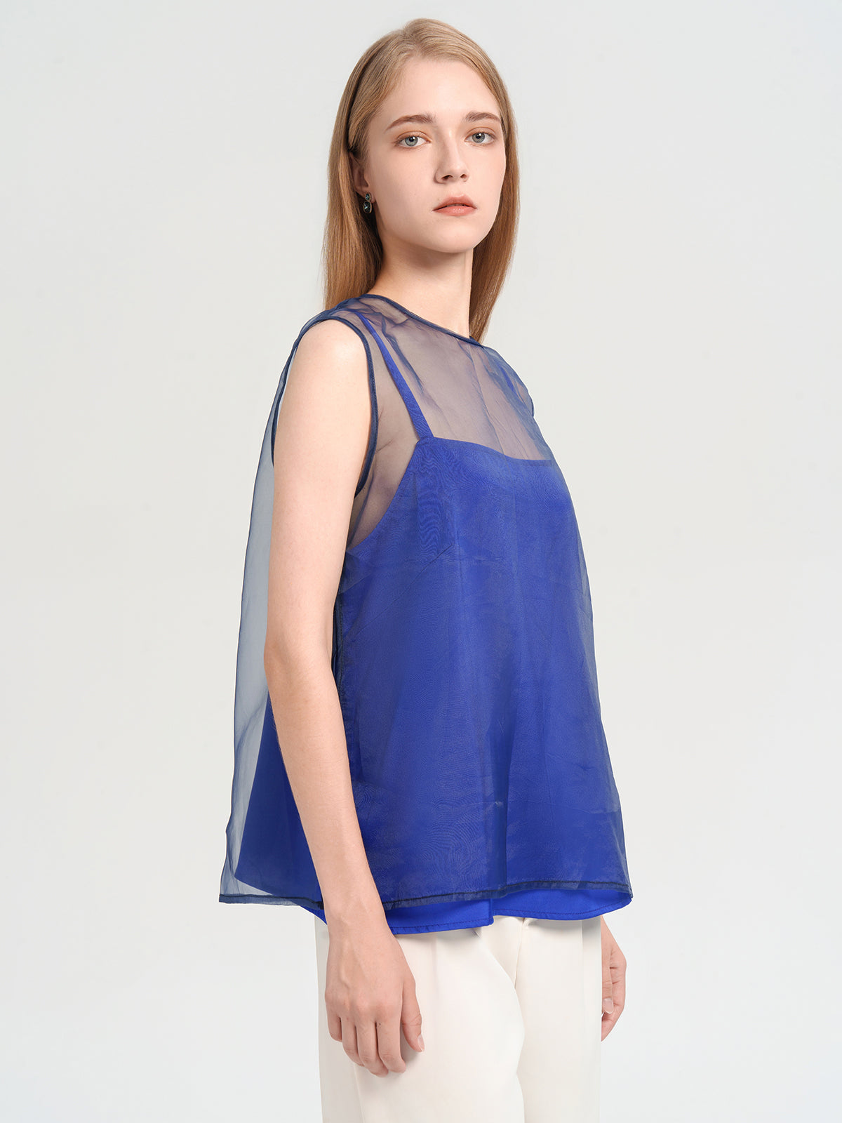 Chic sleeveless blouse featuring a blue camisole with a transparent mesh yoke for a modern layered look