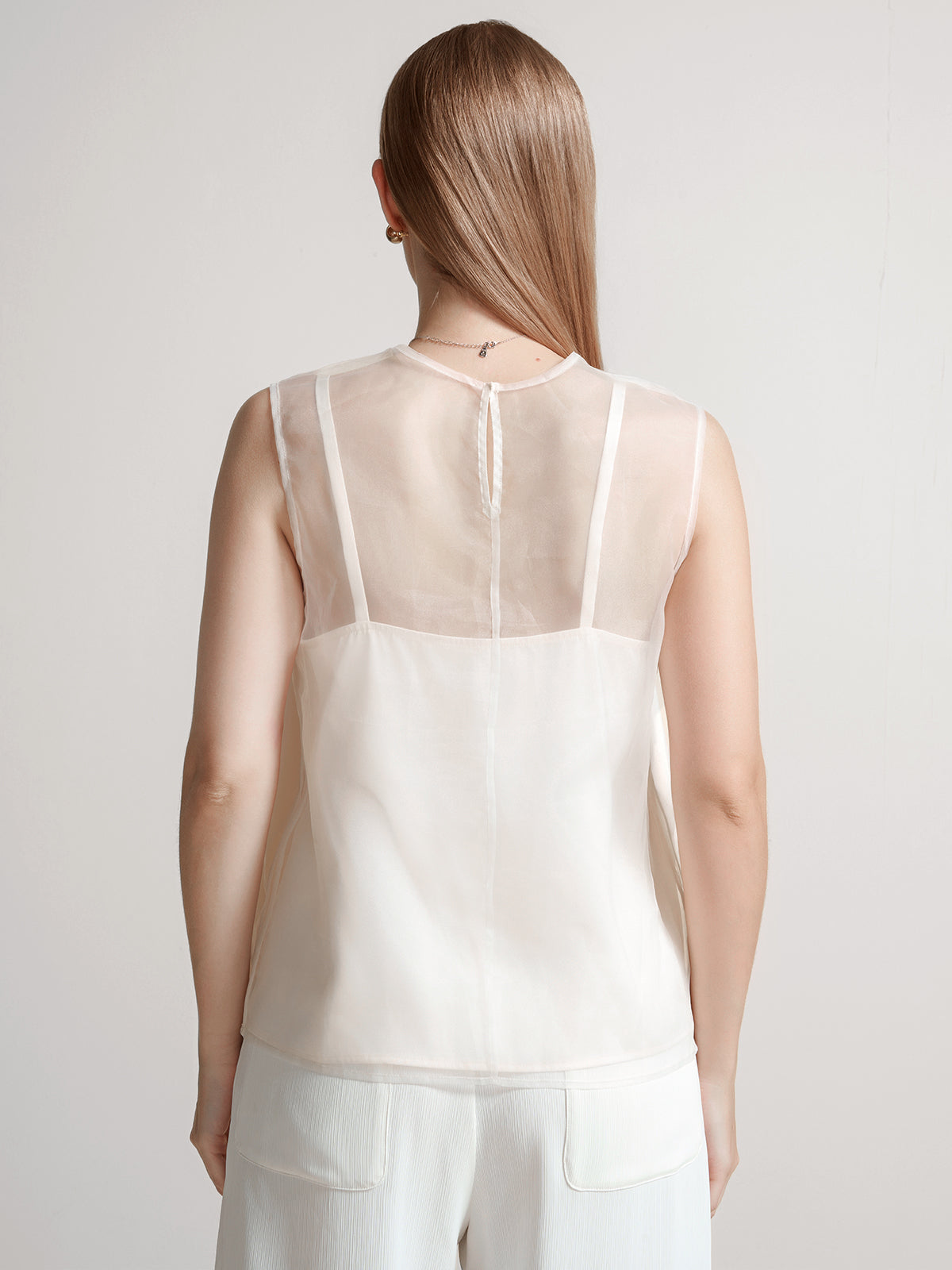 Minimalist sleeveless top in beige with a sheer round-neck overlay for a delicate layered look